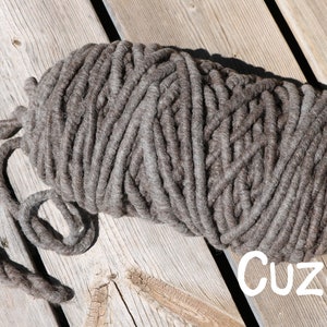 May include: A large, thick skein of dark brown yarn with a chunky, twisted texture. The yarn is wound into an oval shape with a loose end extending to the left. The word "Cuzco" is printed in white, sans-serif letters in the bottom right corner.