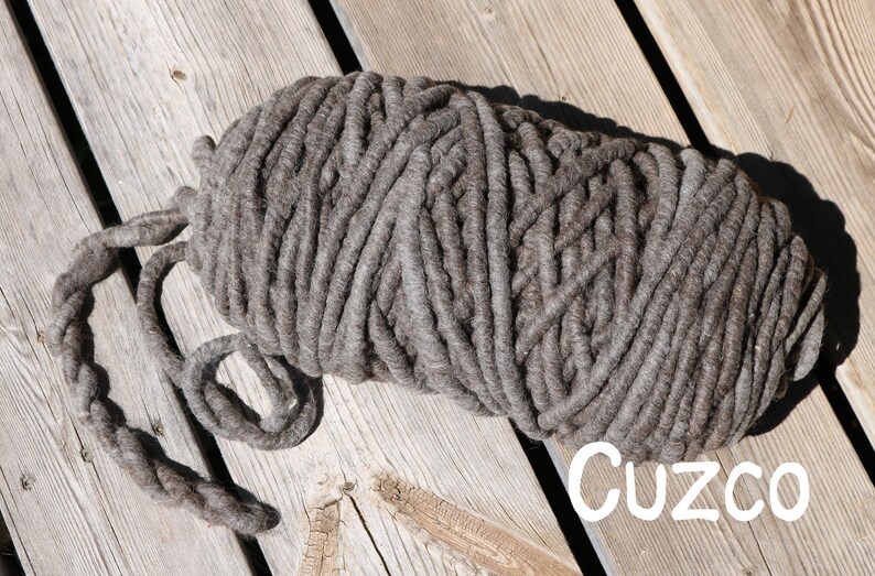 May include: A large, thick skein of dark brown yarn with a chunky, twisted texture. The yarn is wound into an oval shape with a loose end extending to the left. The word "Cuzco" is printed in white, sans-serif letters in the bottom right corner.