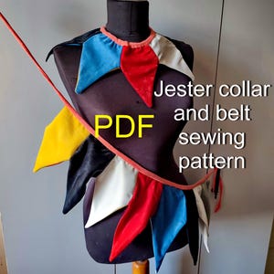 May include: A jester collar and belt sewing pattern PDF featuring a multi-coloured fabric collar with pointed segments in red, blue, white, yellow, and black. A long red fabric belt extends diagonally across the front of the black mannequin torso.
