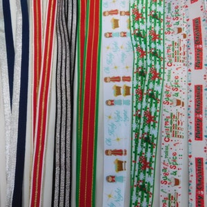 May include: Assorted ribbons in various colors and patterns. Some ribbons have metallic silver or gold accents. Several ribbons feature Christmas-themed designs with text like "Oh Holy Night", "Merry Christmas", and "Sugar makes Christmas & Spice".