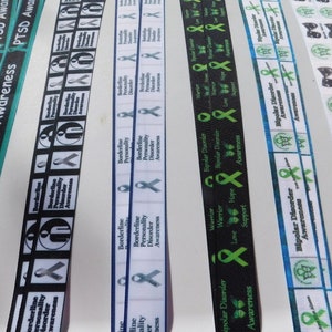 May include: Assortment of black, white, and blue ribbon with green awareness ribbons printed with text such as "Borderline Personality Disorder Awareness", "Bipolar Disorder Awareness", and "PTSD Awareness".