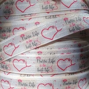 May include: White elastic hair tie with a repeating pattern of pink hearts and the text "Nurse Life Best Life".