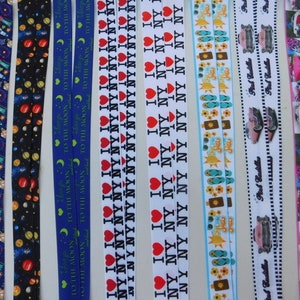 Peut inclure: Un assortiment de rubans colorés avec différents motifs, notamment des étoiles, des planètes, des tongs, des voitures et le texte "I love NY".