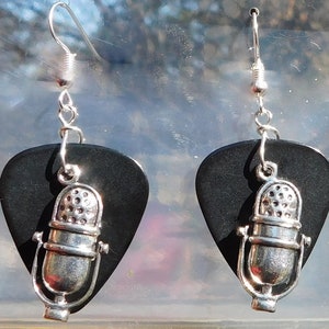 May include: A pair of silver microphone earrings on black guitar picks. The earrings have a silver hook and a silver chain.