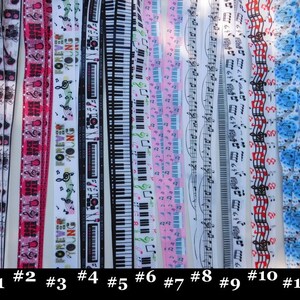May include: A collection of eleven lanyards with various musical and rock-and-roll themed designs. The lanyards feature images of guitars, keyboards, musical notes, and the text "ROCK STAR" and "FOREVER YOUNG". The lanyards are in various colors, including black, white, pink, and blue.