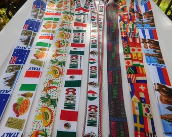 Peut inclure: Un ensemble de dix lanyards colorés avec différents drapeaux de pays et noms de villes imprimés dessus. Les lanyards sont faits d'un tissu blanc avec une bordure noire. Les drapeaux comprennent l'Australie, l'Italie, le Mexique, la Russie et un lanyard multi-drapeaux avec des drapeaux du monde entier. Les noms de villes comprennent Madrid, Paris, Berlin et Londres.