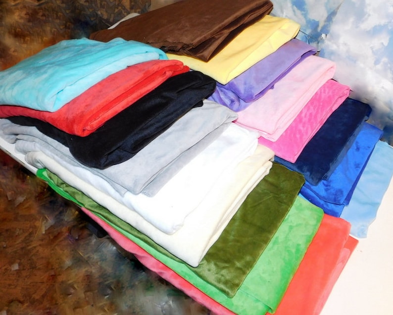 May include: A stack of 18 different colored fabric swatches. The fabrics are folded and stacked on top of each other. The colors include blue, red, black, gray, white, green, and pink.