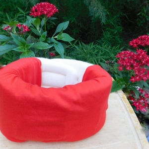 May include: A red and white cervical neck collar for support and comfort. The collar is made of soft, padded material and has a contoured shape to fit the neck.