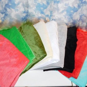 May include: A collection of ten fabric swatches in various colors, including red, green, blue, white, black, and gray. The swatches are arranged in a fan shape on a white surface.