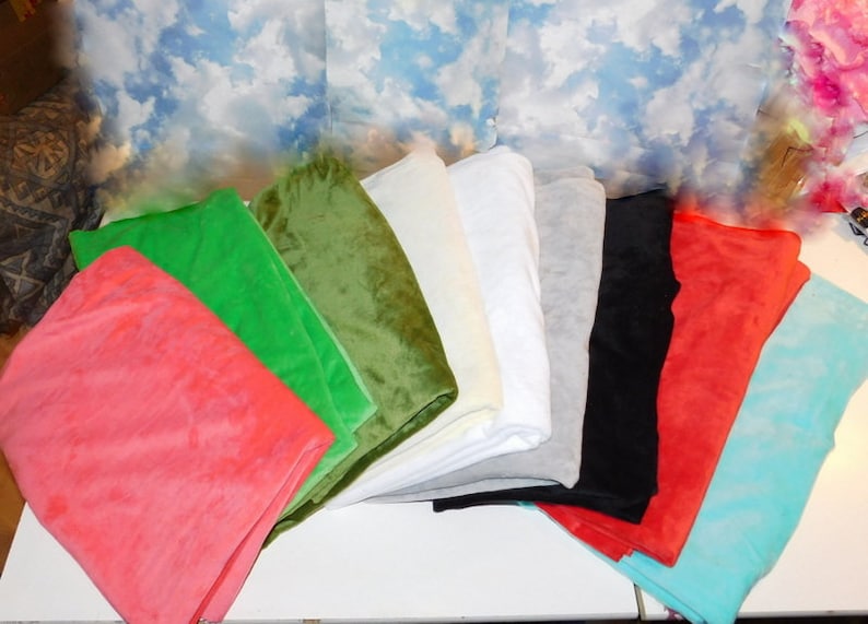 May include: A collection of ten fabric swatches in various colors, including red, green, blue, white, black, and gray. The swatches are arranged in a fan shape on a white surface.