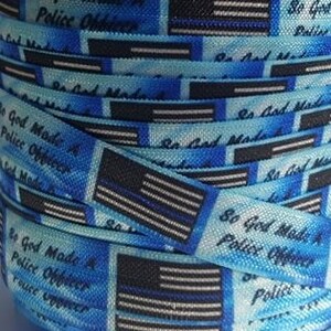 May include: A roll of blue and white ribbon with a thin black line. The ribbon has a repeating pattern of a thin blue line American flag and the text "So God Made A Police Officer".