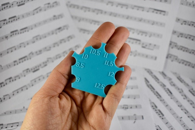May include: A blue plastic ring sizer with measurements from 9 to 12.5 in half-size increments.