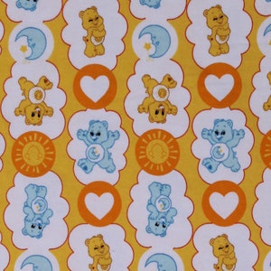 May include: Yellow fabric with a repeating pattern of white clouds, orange circles, and blue and yellow cartoon bears. The bears are holding hearts, moons, and suns.