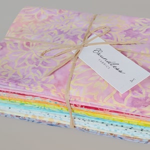 May include: A stack of 12 colorful fabric squares tied with twine and a tag that reads "Boundless Fabrics". The fabric squares are a variety of pastel colors with floral patterns.