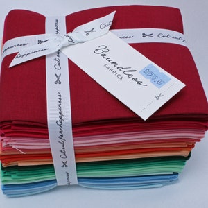 May include: A stack of 20 fabric squares in various shades of red, pink, orange, green, blue, and light blue. The fabric squares are tied together with a white ribbon that says "Cut out for happiness". A white tag with the text "Boundless Fabrics" and "DH535.07" is attached to the top of the stack.