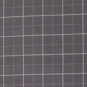May include: A dark gray fabric with a white grid pattern. The grid is composed of solid and dotted lines, creating a visual texture. The bottom edge of the fabric has a ruler with inch measurements.