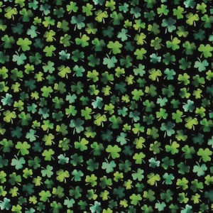 May include: Black fabric with a repeating pattern of green shamrocks. The fabric is shown with a ruler for scale.