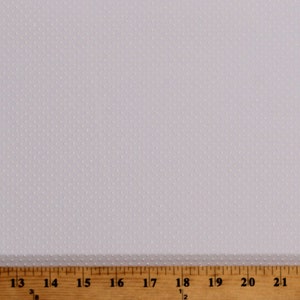Peut inclure: Tissu blanc avec un motif de points blancs subtils et espacés uniformément. Une règle en bois avec des marques en pouces se trouve en bas de l'image.