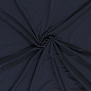 May include: A close-up of a dark blue fabric with a smooth texture. The fabric is folded and draped, creating soft folds and curves.