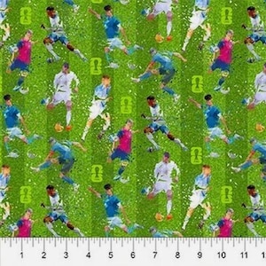 May include: Green fabric with a repeating pattern of soccer players in action. The players are wearing various colored uniforms, including blue, white, and pink. The background features green grass and soccer field markings.
