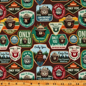 May include: A brown fabric with a repeating pattern of colorful patches featuring Smokey Bear. The patches have various slogans, including "Only You Can Prevent Wildfires", "Keep It Green", and "Always Be Careful".