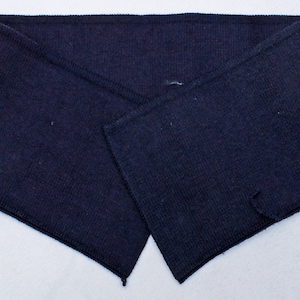 May include: A dark blue knitted collar with a pointed shape. The collar is folded in half and has a seam down the center.
