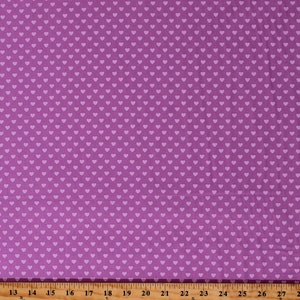 May include: Purple fabric with a white heart pattern. The fabric is measured with a ruler in inches.