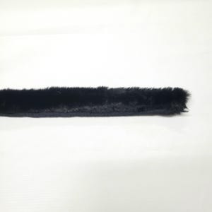 May include: A strip of black faux fur trim, with a dark fabric backing. The fur is dense and plush, creating a soft, textured appearance. The trim is likely used for clothing or craft projects.