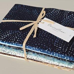 May include: A stack of 10 fat quarters of blue and white batik fabric, tied with twine and a tag that reads "Boundless Fabrics".