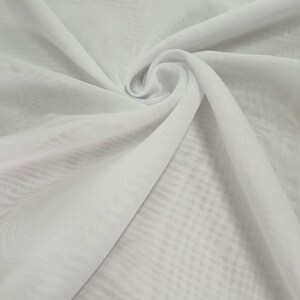 May include: A sheer white fabric featuring a subtle, repeating grid pattern. The material is gathered into a central swirl, creating soft, flowing folds and drapes that highlight the translucent quality and the delicate texture of the textile.