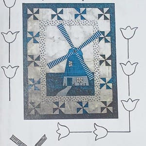 May include: A quilt pattern for a wall hanging featuring a blue windmill with white stripes against a white background with blue and black accents. The pattern is titled "Windmill in Blue" and measures 29 1/2 inches by 36 1/2 inches. The pattern is copyrighted 1994 by Helen Estergreen.