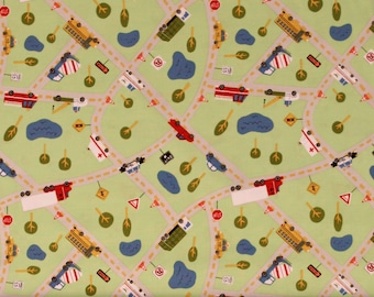 May include: A green fabric with a repeating pattern of various vehicles, including trucks, cars, and construction vehicles. The vehicles are driving on a yellow road with blue ponds and green trees. The fabric has a ruler at the bottom with inches marked.