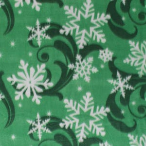 May include: Green fleece fabric with a repeating pattern of white snowflakes and dark green swirling leaf designs. The fabric has a soft, plush texture and is suitable for winter-themed crafts and apparel.