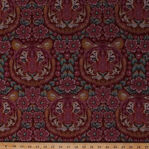 May include: A red fabric with a repeating pattern of tiger faces and pink flowers. The fabric has a woven texture.
