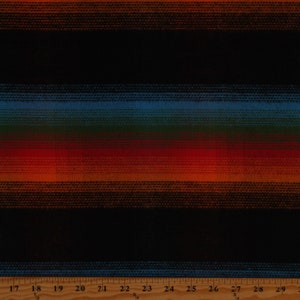 May include: Striped fabric with a black background and horizontal stripes in shades of orange, red, green, and blue. The fabric is measured with a ruler in inches.