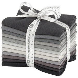 May include: A stack of 15 fabric squares in shades of gray, from light to dark, tied with a white ribbon. The fabric is a solid color and has a smooth texture.