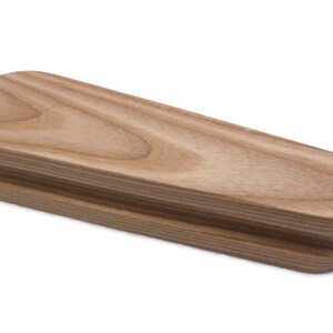 May include: A wooden oval-shaped object with a smooth, light brown finish. The object is made of two pieces of wood that are joined together.