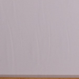 May include: A close-up of a white fabric with a subtle texture. The fabric is measured with a wooden ruler, showing markings from 19 to 28 inches.