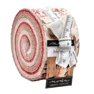 May include: A rolled bundle of fabric strips in shades of red, cream, and tan. The fabric is patterned with floral designs. A white ribbon with measurement markings and the word "Joie" is wrapped around the bundle. A tag with the words "moda FABRICS SUPPLIES" is attached.