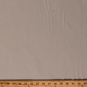 May include: A close-up of a plain, light beige fabric with a slight sheen. The fabric is smooth and wrinkle-free.