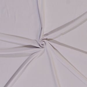 May include: White fabric with a smooth, silky texture. The fabric is folded and twisted in the center, creating a spiral pattern.