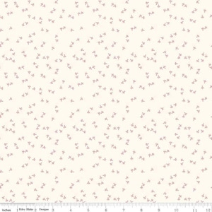 May include: Cream-coloured fabric featuring a repeating pattern of small, mauve floral sprigs. The fabric is measured in inches, with a ruler along the bottom edge. The Riley Blake Designs logo is visible.