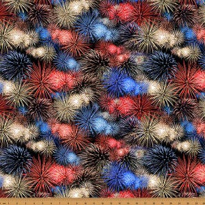 May include: A fabric pattern featuring a dense, repeating display of fireworks in shades of red, white, and blue against a black background. A ruler at the bottom edge shows measurements in centimetres, spanning from 0 to 24 centimetres across the width.