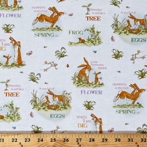 May include: A white fabric with a repeating pattern of brown rabbits, green leaves, and blue text. The text includes "Flower", "Spring", "Frog", "Eggs", "Someday it will be a Tree", "Hopping in the fresh", "When I am Big", and "Little Nutbrown Hare".