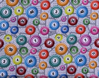 May include: Fabric with a repeating pattern of colorful bingo balls and bingo cards. The balls are in various colors, including orange, green, blue, and purple, each with a number. The background features a light gray bingo card design.