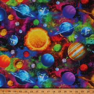 May include: A colorful fabric with a repeating pattern of planets and stars in a galaxy. The fabric features a bright yellow sun, blue, green, and purple planets, and a dark blue background with white and pink nebulae.
