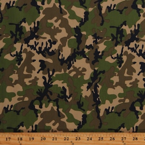 May include: Camouflage fabric with a repeating pattern of green, brown, and black shapes. The fabric is measured with a ruler in inches.