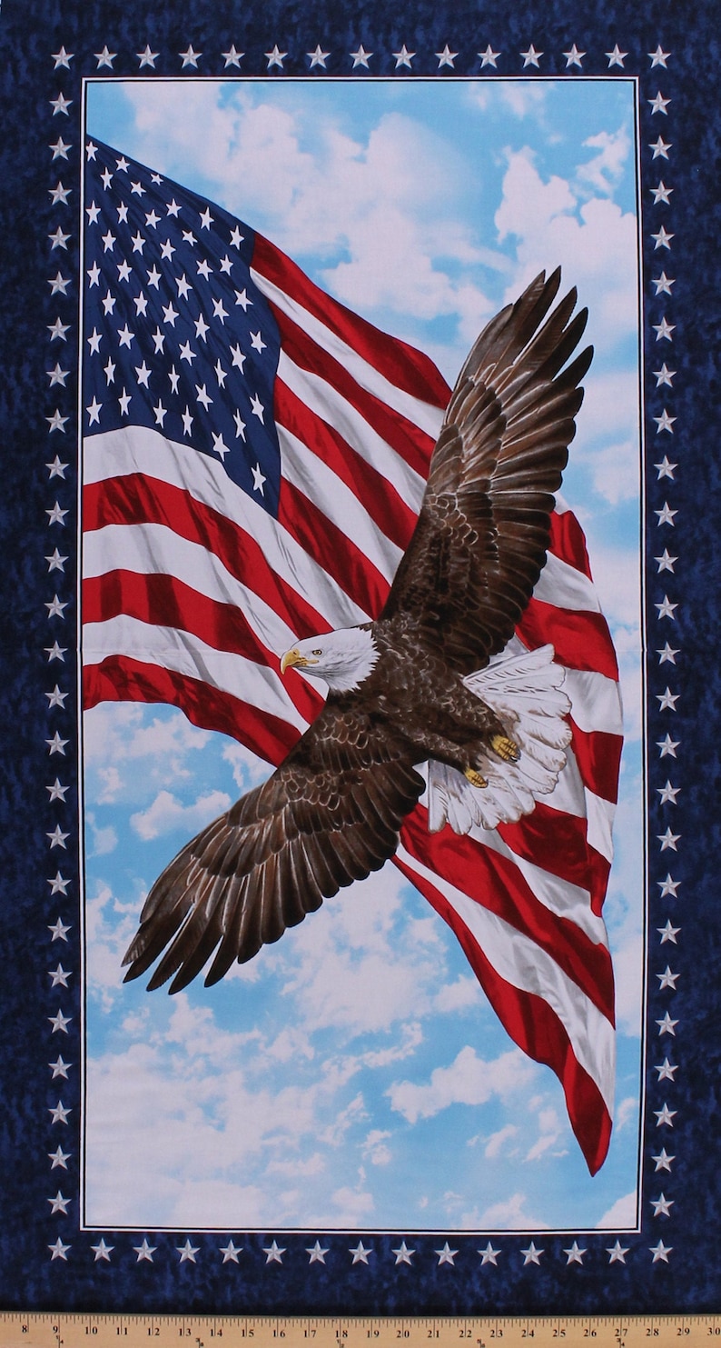 May include: A bald eagle in flight with its wings spread wide, soaring above an American flag waving in the wind against a blue sky with white clouds. The flag is red, white, and blue with white stars on a blue field.