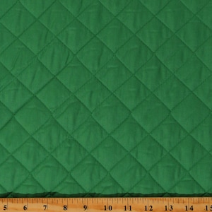 May include: Green quilted fabric with a diamond pattern. The fabric is measured with a ruler in inches.