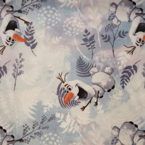 May include: Light blue fleece fabric featuring a repeating pattern of Olaf the snowman from Frozen, with a carrot nose and twig hair. The design includes white and purple floral and foliage elements, creating a whimsical, wintery theme.
